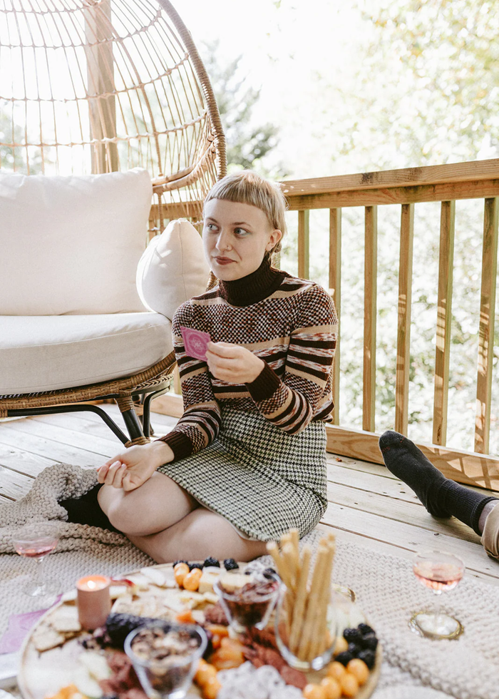 Woman sitting on a deck with a card in her hand
