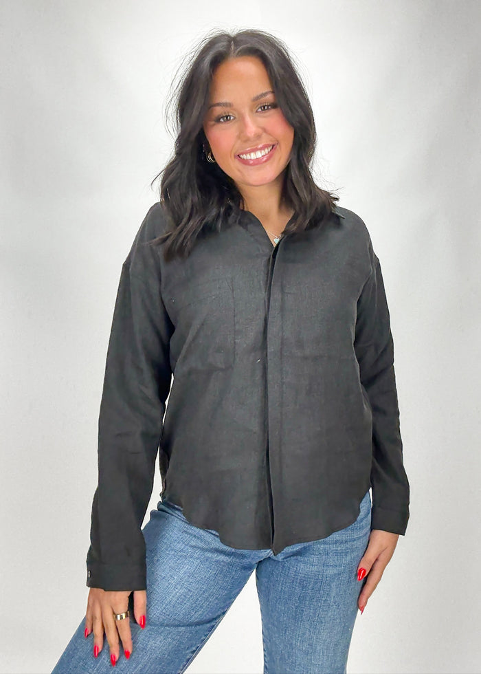 Woman wearing a dark gray button-up shirt and blue jeans on a white background