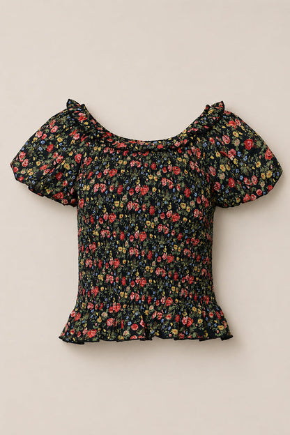 The Annalise Top in Obsidian Vintage Poppies by Ivy City Co is a black, short-sleeved floral top with puff sleeves, a ruffled neckline and hem, red, yellow, and pink flowers, plus a chic smocked bodice.