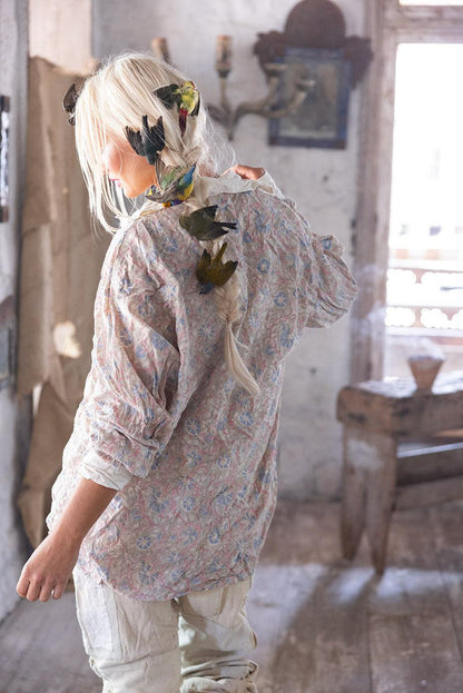 Woman in Magnolia Pearl artisan floral blouse, whimsical birds in hair, vintage rustic room