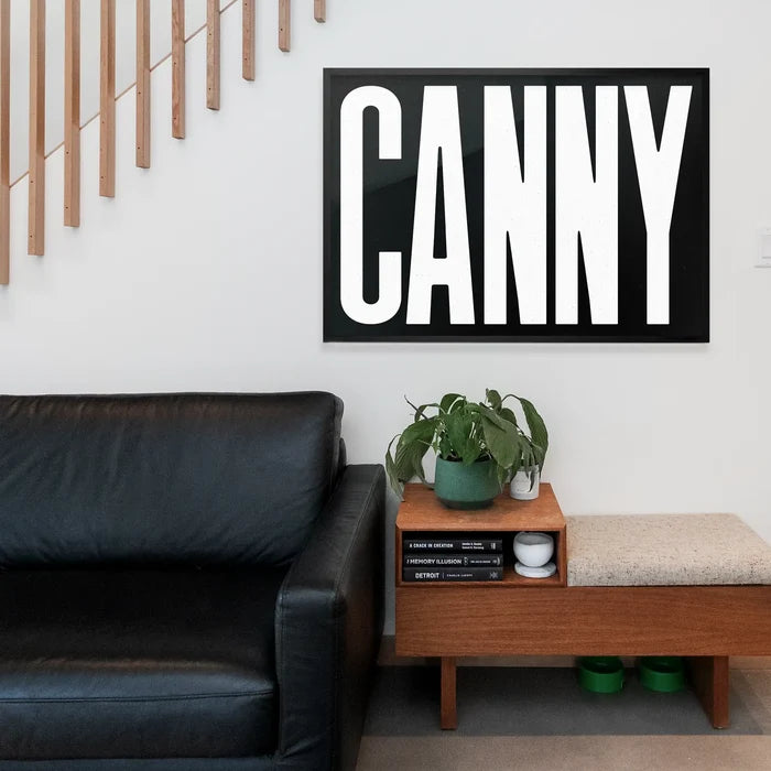 Canny Typography Poster Black and White Print framed above a living room sofa