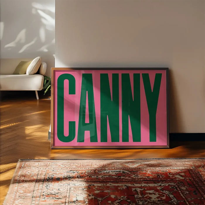 Canny Typography Poster Print framed, leaning on a wooden floor beside a rug