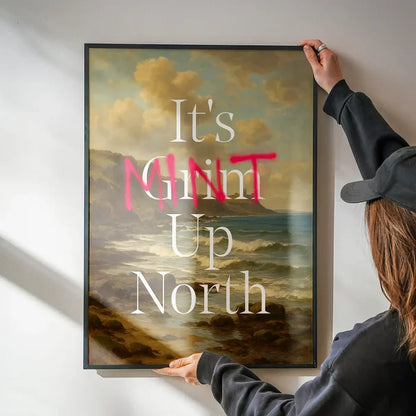 It's Mint Up North Typography Poster being hung on a wall in a black frame