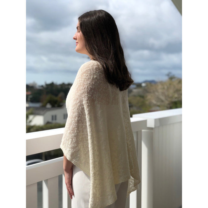Woman wearing cotton poncho. Colour Cream