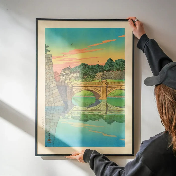 Morning at Niju Bridge Print by Hasui Kawase being hung on a wall in a black frame