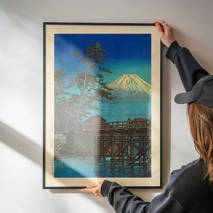 Mt. Fuji in Moonlight and Kawaibashi Bridge Print by Hasui Kawase being hung on a wall in a black frame