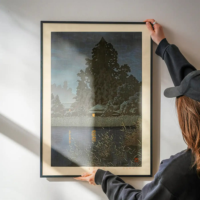 Rain at Omiya Print by Hasui Kawase being hung on a wall in a black frame