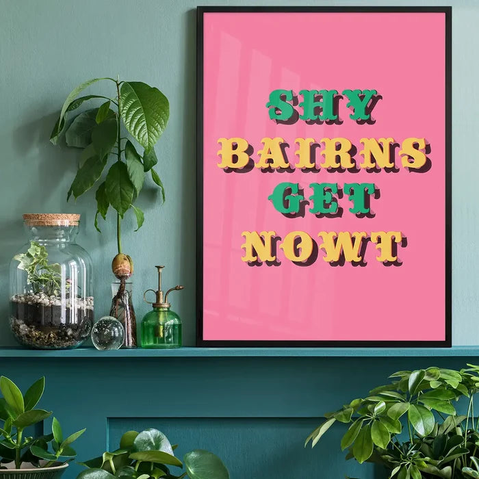 Shy Bairns Quote Print Pink And Green black framed on a living room shelf