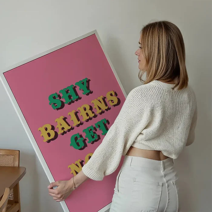 Shy Bairns Quote Print Pink And Green held up against a living room wall