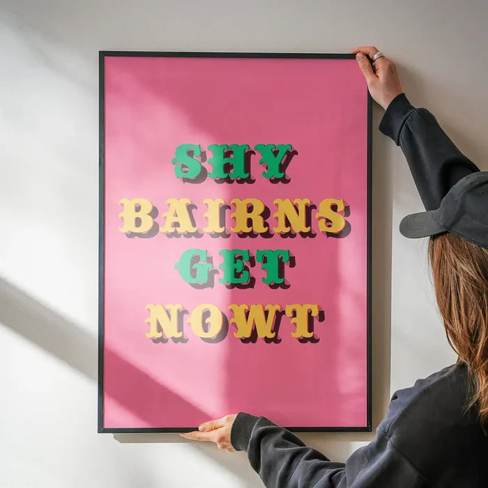 Shy Bairns Quote Print Pink And Green being hung on a wall in a black frame