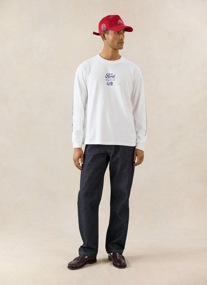 White Ford x Percival Triple Triumph long sleeve t-shirt worn with straight leg heritage denim jeans and a red cap.