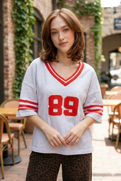 Oversized varsity jersey, women's sporty tee, retro athletic shirt, game day outfits, oversized jersey top, vintage varsity style, cool girl aesthetic clothing, grey varsity shirt.