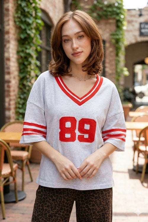 Oversized varsity jersey, women's sporty tee, retro athletic shirt, game day outfits, oversized jersey top, vintage varsity style, cool girl aesthetic clothing, grey varsity shirt.