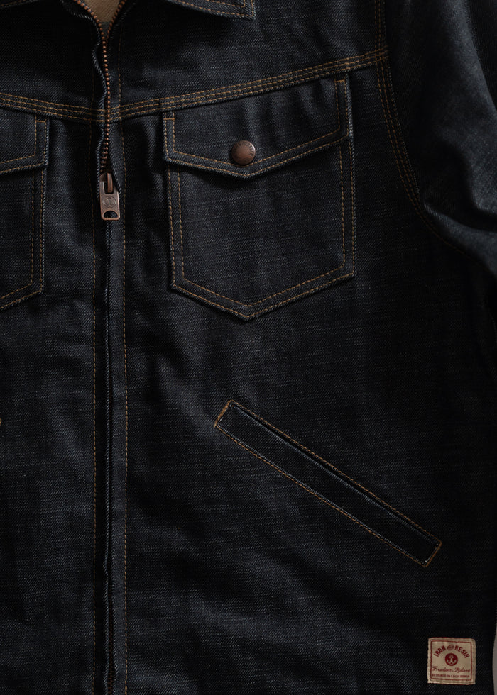 Dark denim jacket with front zipper, two chest pockets with buttons, and a small label at the bottom right corner.