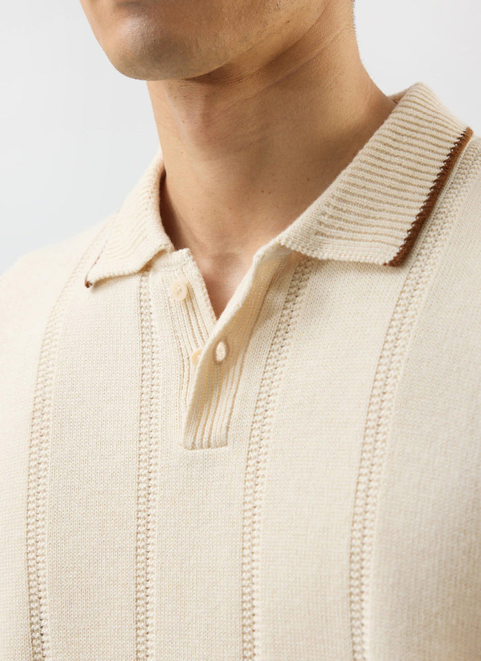 A close-up of the Percival x Warren knitted polo in ecru, detailing the vertical texture and contrast tipping on the collar.