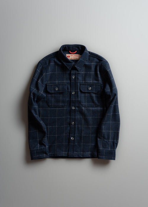 Dark plaid button-up shirt with two chest pockets, laid flat on a light gray background.